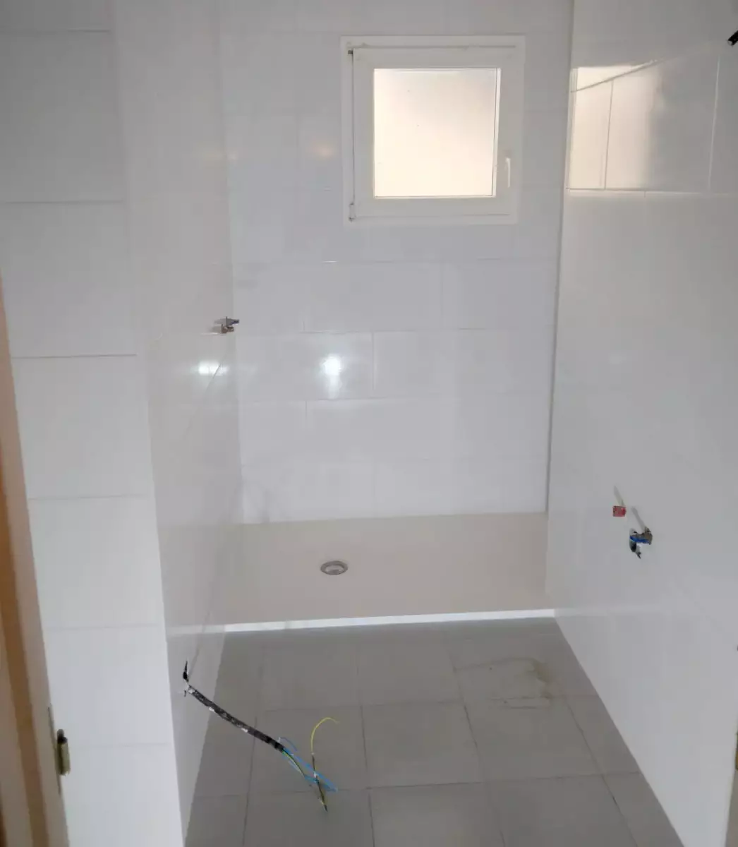 Baño reformado con plato de ducha y azulejo blanco en Córdoba